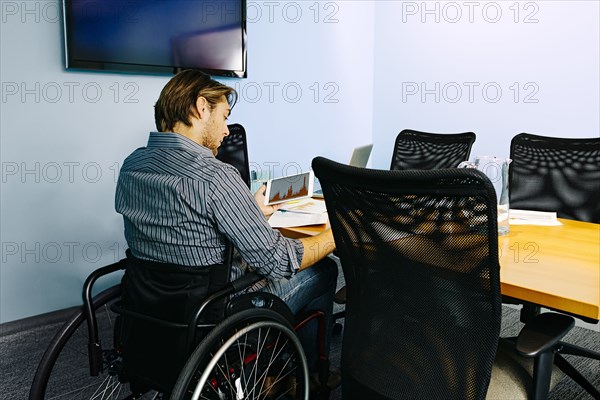 Businessman in wheelchair working at desk in office