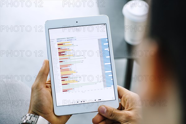 Mixed race businessman examining graph on digital tablet