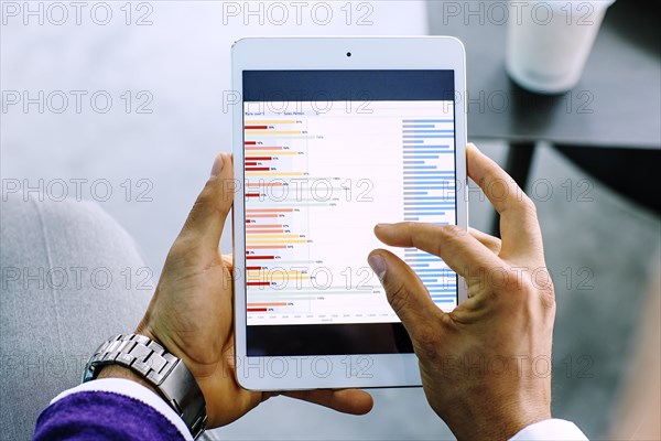 Mixed race businessman examining graph on digital tablet
