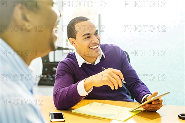 Businessmen laughing in office meeting