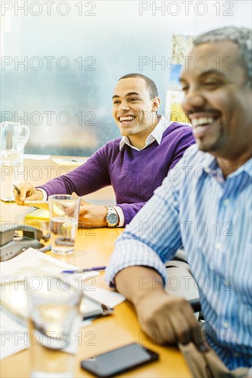 Businessmen laughing in office meeting