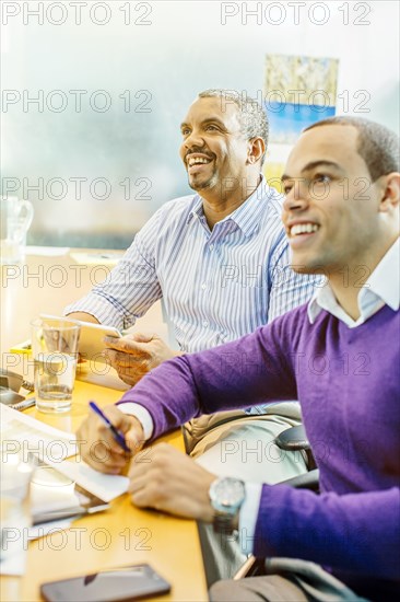 Businessmen laughing in office meeting