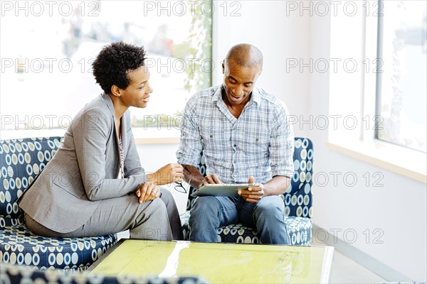 Black business people using digital tablet in office lobby