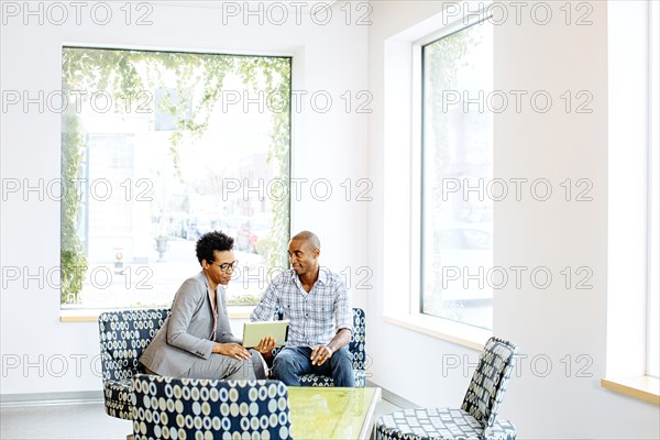 Black business people using digital tablet in office lobby