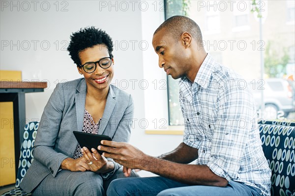 Black business people using digital tablet in office lobby