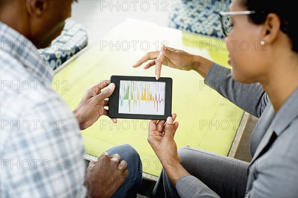 Black business people using digital tablet in office lobby
