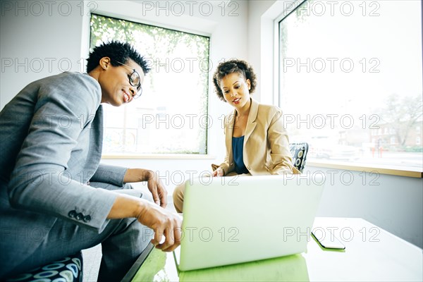 Businesswomen using laptop in office lobby