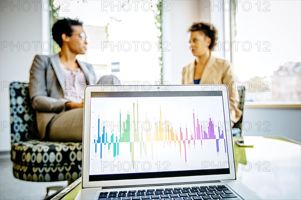 Businesswomen sitting behind laptop in office lobby