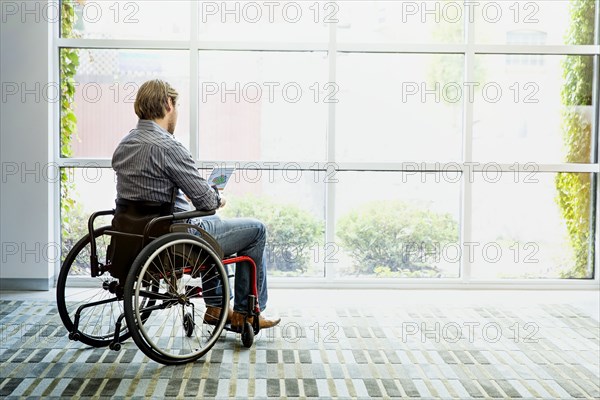 Businessman in wheelchair using digital tablet in office