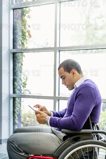 Businessman in wheelchair using digital tablet in office