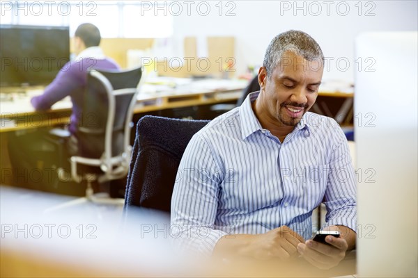 Businessman using cell phone at office desk