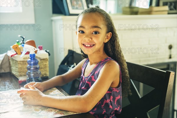 Mixed race girl smiling at kitchen table