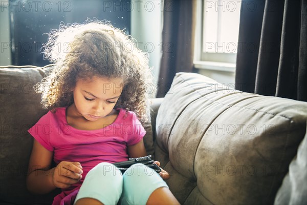 Mixed race girl using digital tablet on sofa