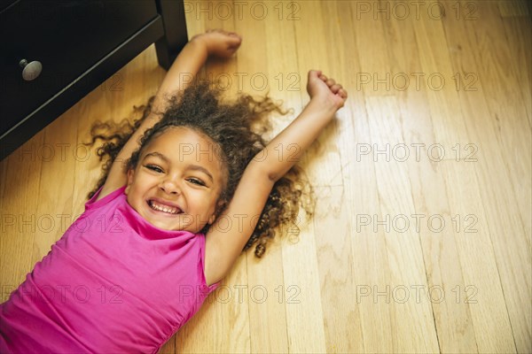 Mixed race girl smiling on wooden floor