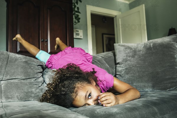 Mixed race girl playing on sofa