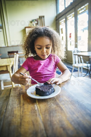 Mixed race girl eating dessert in cafe