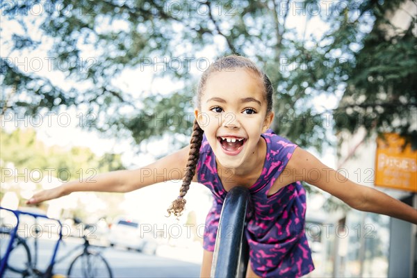 Mixed race girl playing on bicycle rack