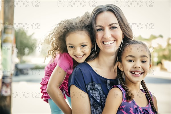 Mother and daughters smiling outdoors