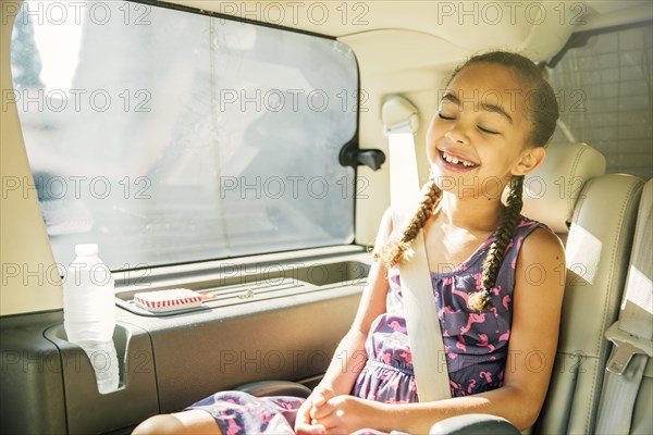 Mixed race girl smiling in back seat of car