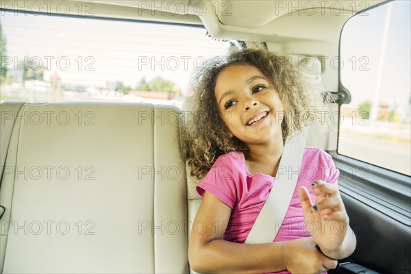 Mixed race girl smiling in back seat of car