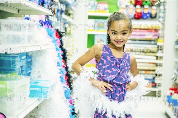 Mixed race girl playing dress-up in party store