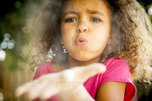 Mixed race girl blowing chalk dust from open palm