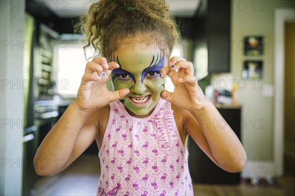 Mixed race girl growling with face paint