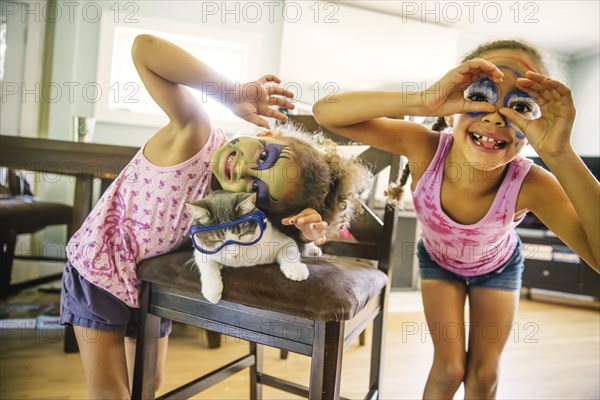 Mixed race sisters playing with face paint and googly eyes