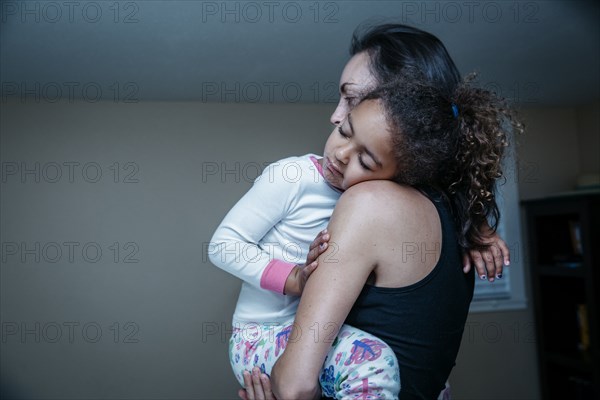 Mother carrying sleepy daughter