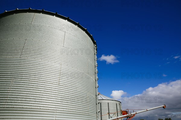 Low angle view of silos under blue sky