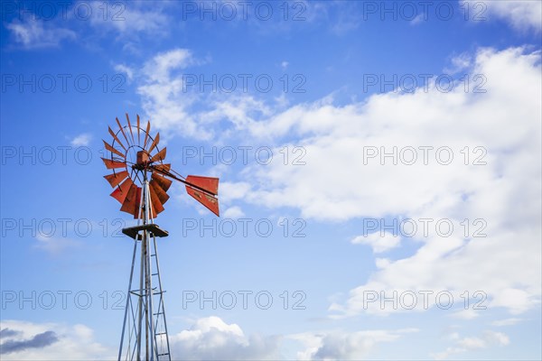 Low angle view of windmill turning under blue sky