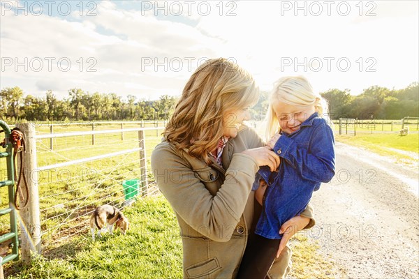 Caucasian mother tickling daughter on rural road