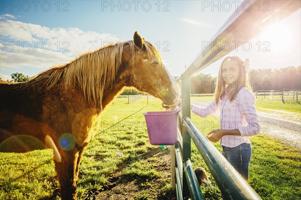 Caucasian girl feeding horse on ranch