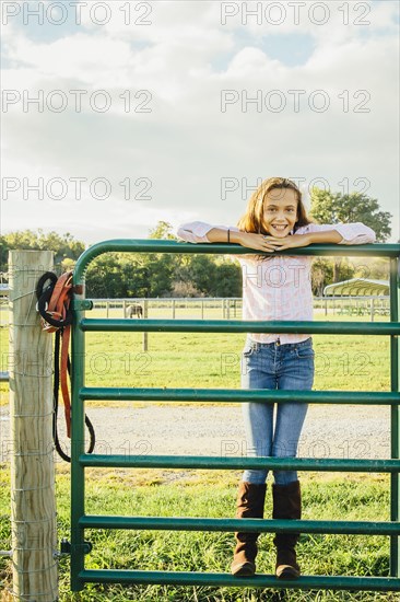 Caucasian girl standing on fence on ranch