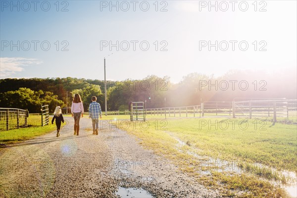 Caucasian children walking on dirt road on ranch