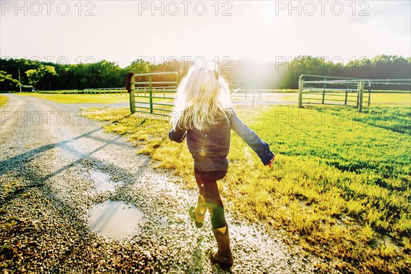 Caucasian girl walking on dirt road on ranch