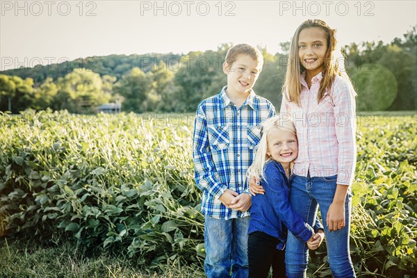 Caucasian children standing in crop field on farm