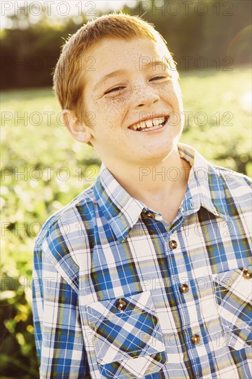 Caucasian boy smiling in crop field on farm