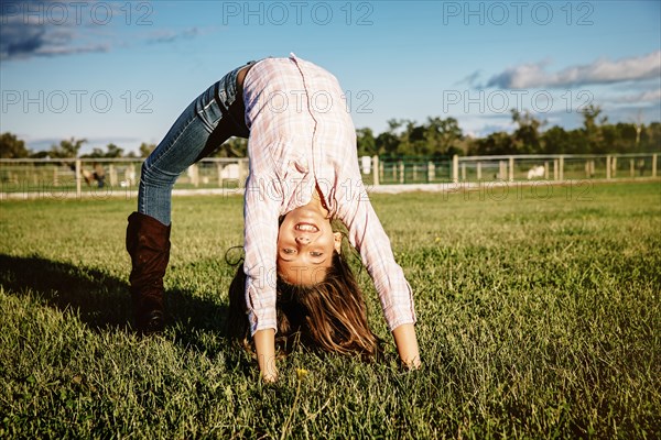 Caucasian girl doing bridge in field on ranch