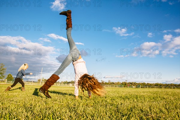 Caucasian girls playing in rural field