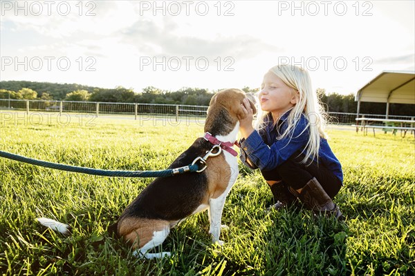 Caucasian girl kissing puppy on farm