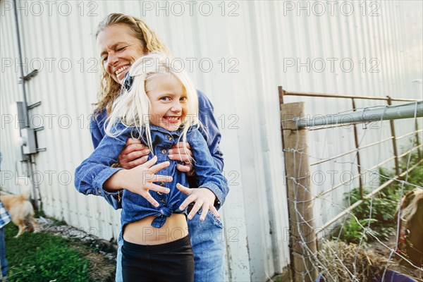 Caucasian mother playing with daughter on farm