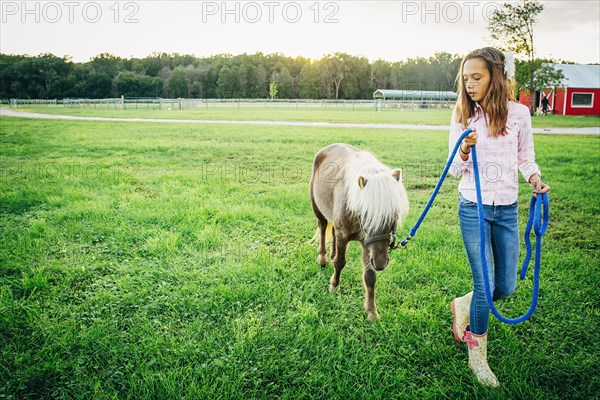 Caucasian girl walking miniature horse on farm