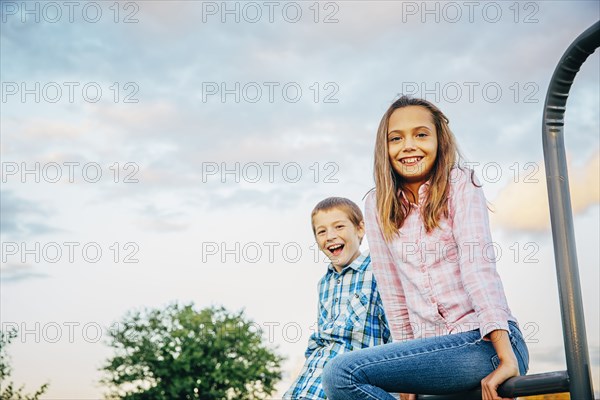 Low angle view of Caucasian children sitting outdoors