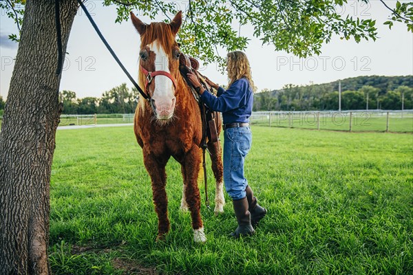 Caucasian woman brushing hair of horse on farm