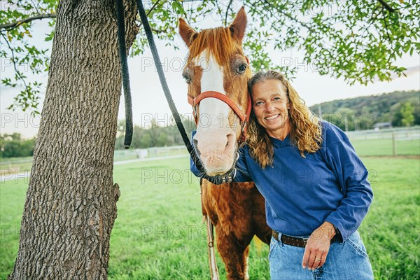 Caucasian woman hugging horse on farm