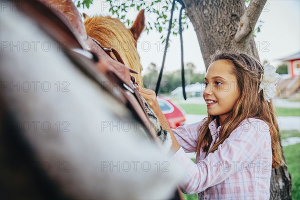 Caucasian girl fastening saddle on horse