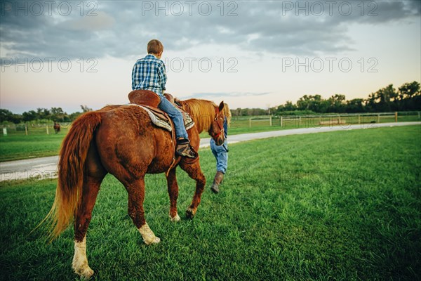 Caucasian mother and son walking horse on ranch