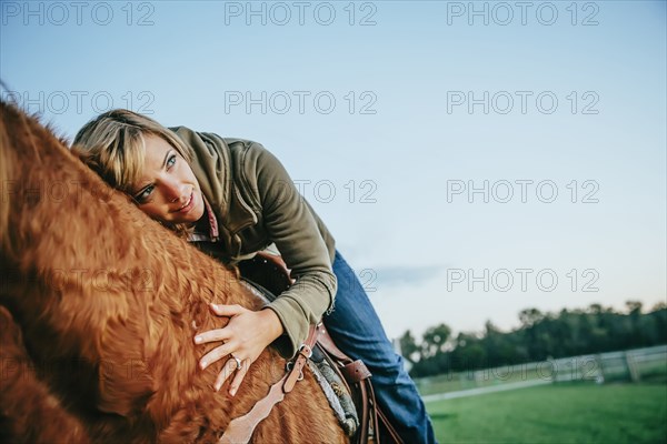 Caucasian woman riding horse on ranch