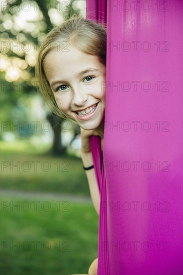 Acrobatic Caucasian girl sitting in hanging fabric